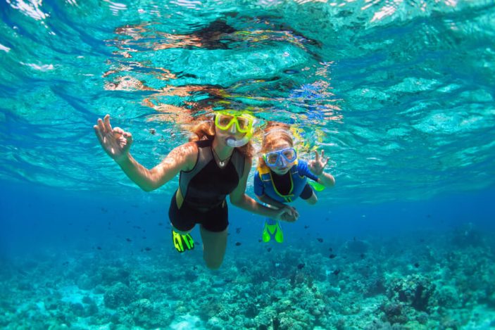 adult and child snorkelling in the ocean.